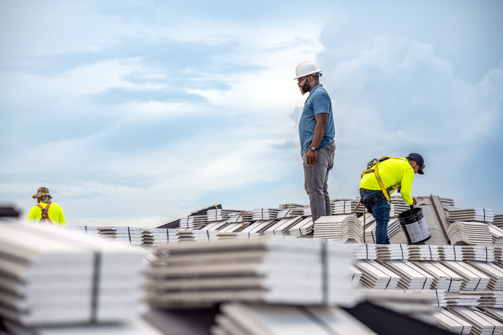 Campany roofers standing among a field of staged white roof tile against a dramatic sky